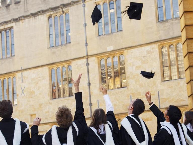 Bachelors der University of Oxford in Grossbritannien werfen ihre Hüte in die Luft vor dem Universitätsgebäude.