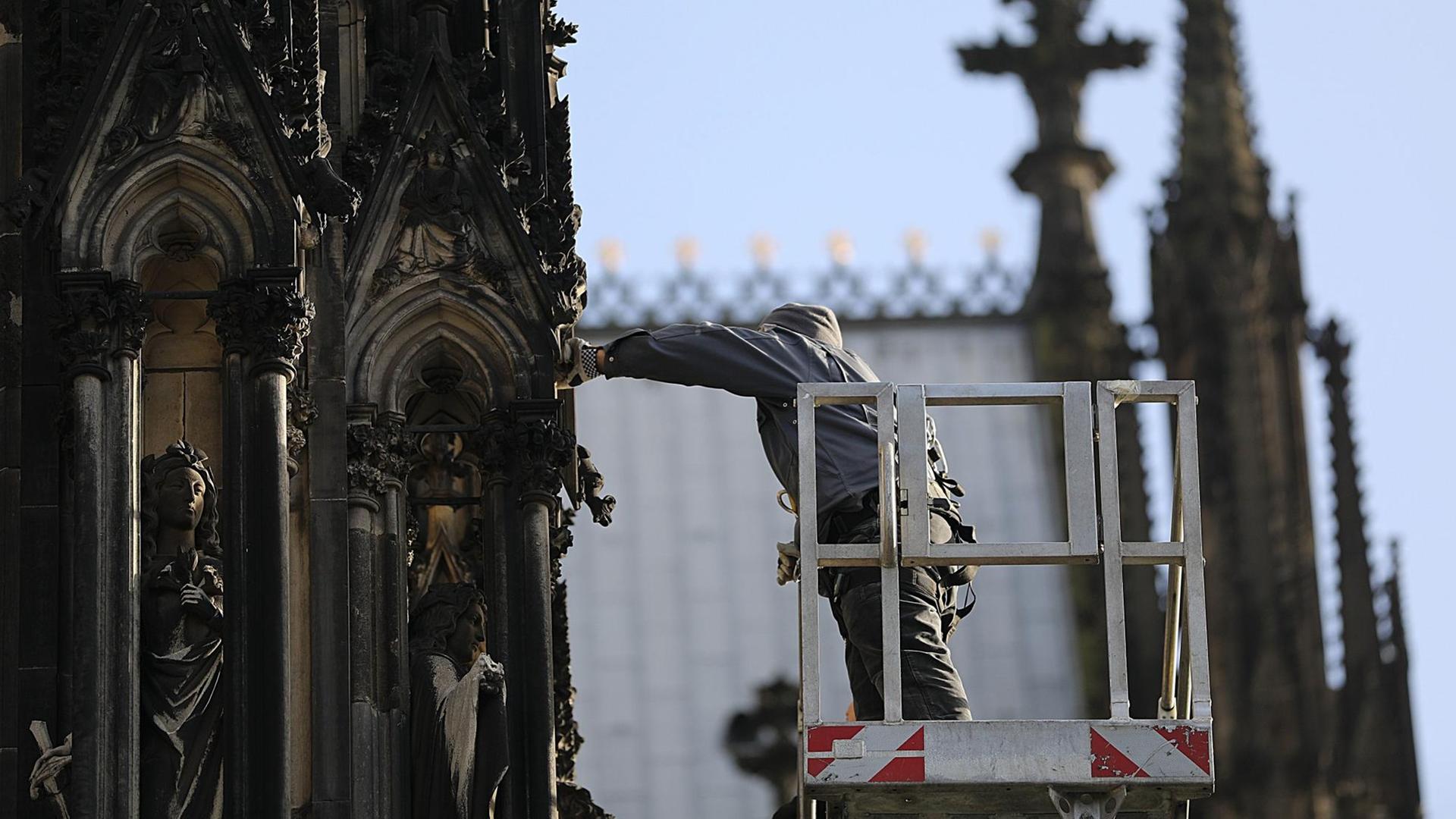 Ein Mitarbeiter der Kölner Dombauhütte überprüft die Figuren und Verzierungen an der Fassade.