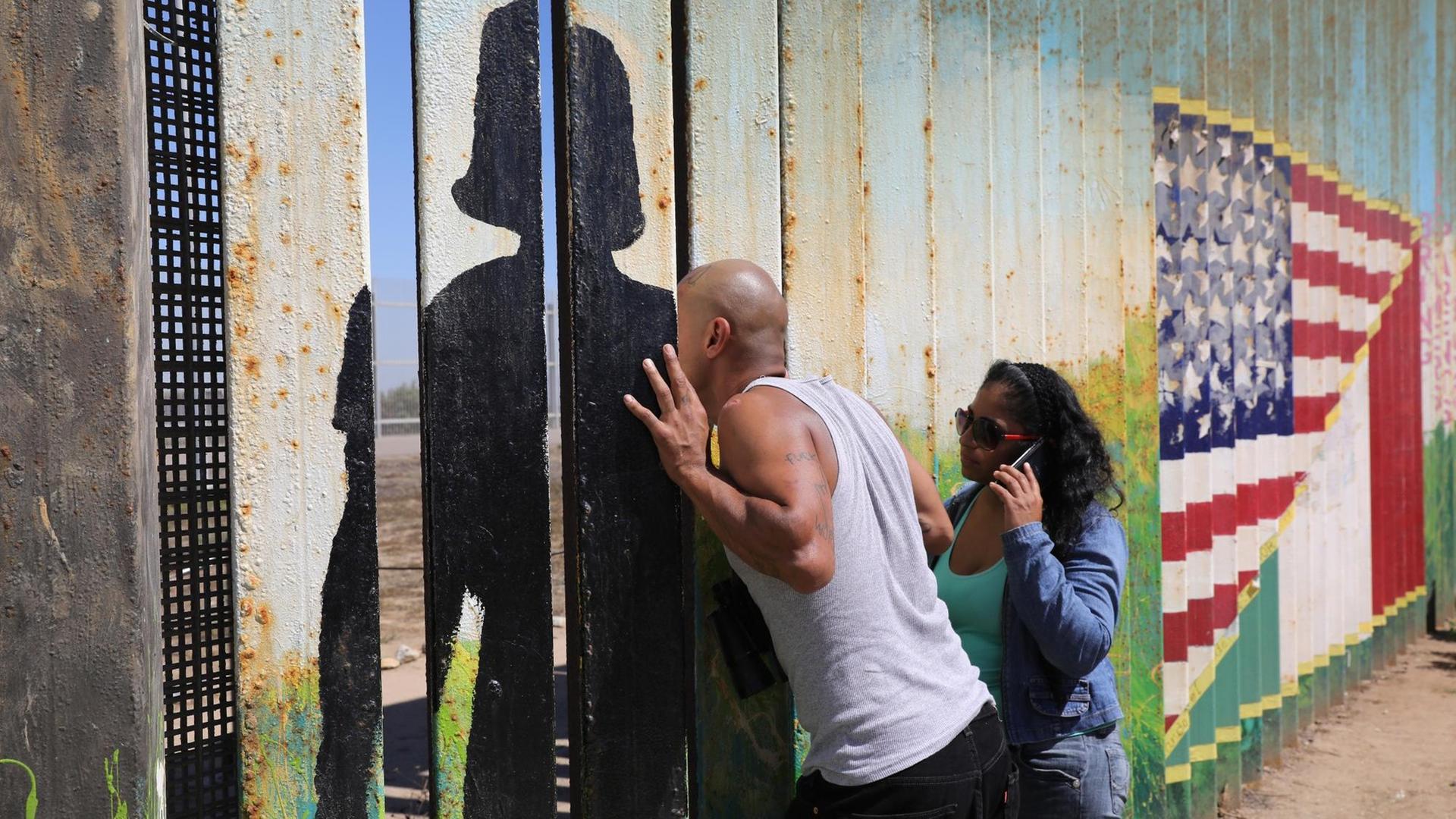Ein Deportierter spricht auf der mexikanischen Seite in Tijuana durch den amerikanisch-mexikanischen Grenzzaun mit Angehörigen auf amerikanischer Seite. US-Grenzschutzbeamte ermöglichen es den Menschen, sich am Wochenende im "Friendship Park" auf der Seite der Grenze von San Diego mit Familie und Freunden auf der mexikanischen Seite über den Zaun zu treffen. Der Park ist einer der wenigen Orte an der 2.000 Meilen langen Grenze, an dem sich Familien, viele von ihnen durch Deportationen getrennt, treffen dürfen.
