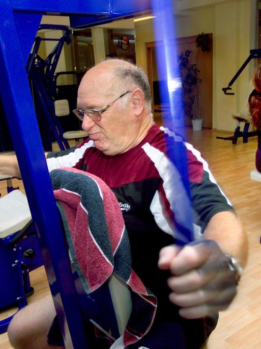 Ein älterer Mann beim ausgiebigen Training der Arme an einem speziellen Trainingsgerät.