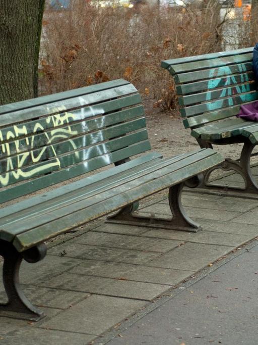 Ein Obdachloser schläft in Berlin auf einer Parkbank