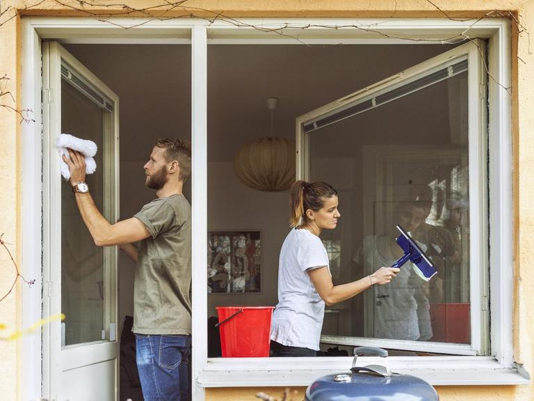 Ein Mann und eine Frau putzen gemeinsam die Fenster.