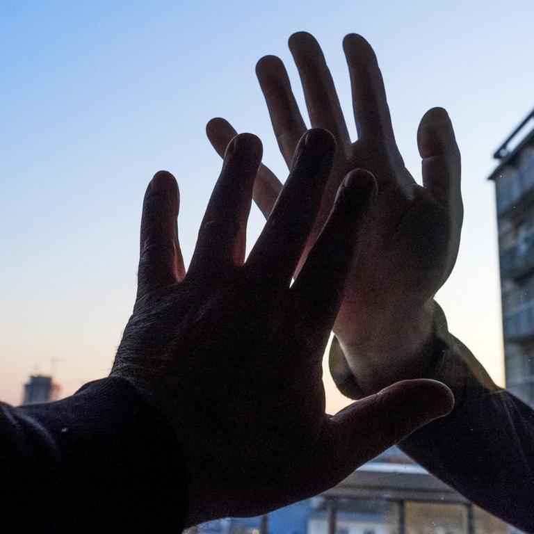Hände an einer Scheibe: Die soziale Distanz während der Coronakrise ist für viele belastend.