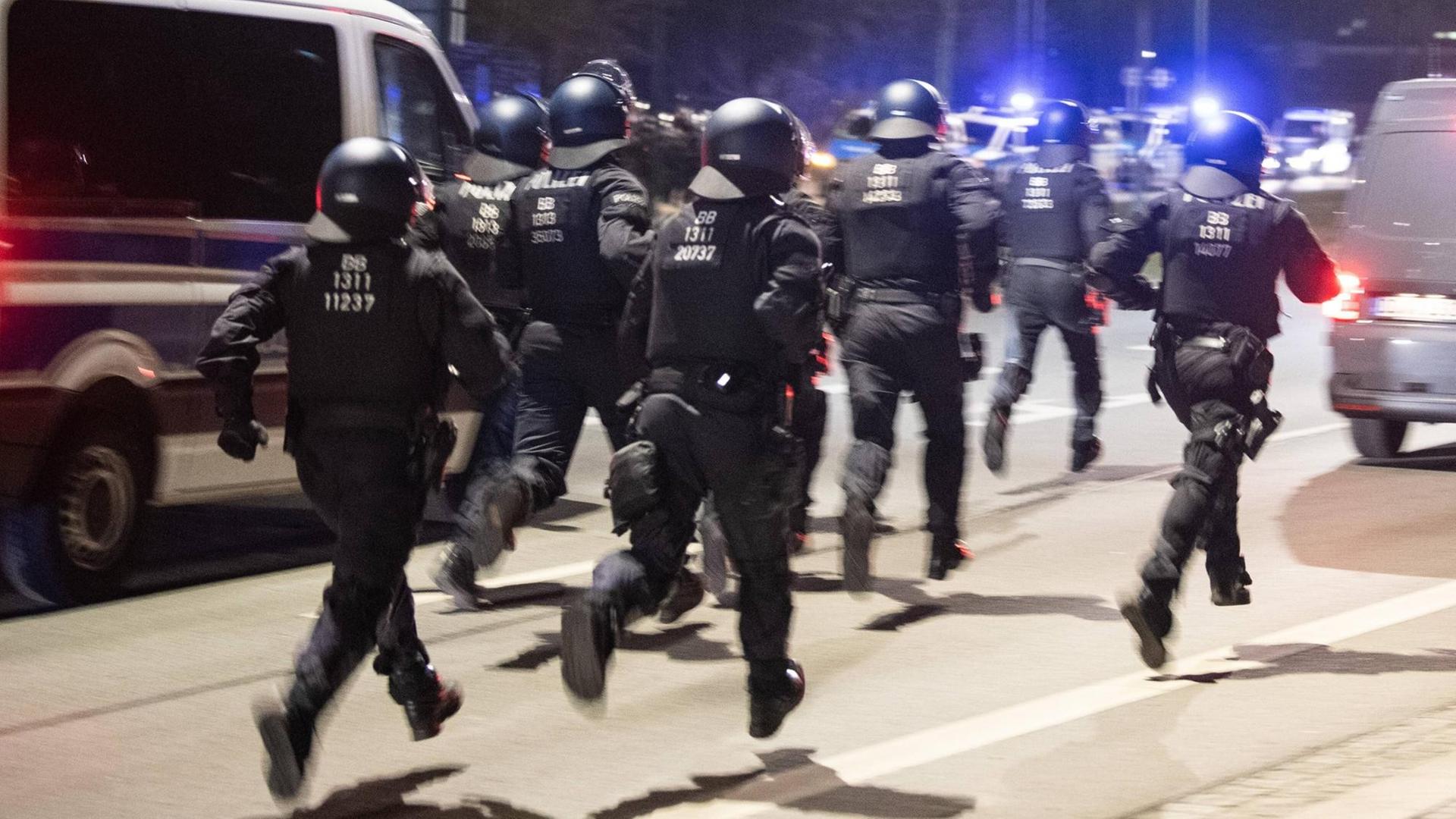 Polizisten rennen in Dresden auf einer Straße entlang.