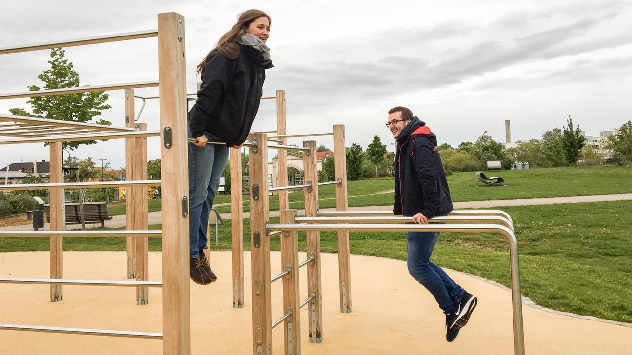 Sophia Faißt und Philipp Schreiner vom Jugendkomitee hangeln sich auf einem Gerüst im "Calisthenics Park" in Bad Dürkheim entlang.