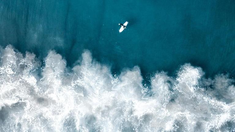 Luftaufnahme eines Surfers und Wellen