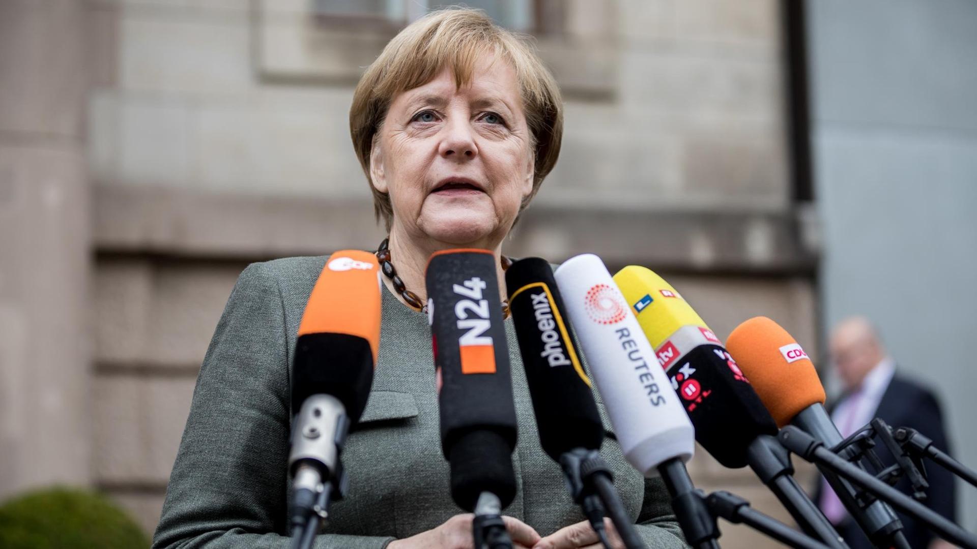 Merkel spricht in mehrere Radio- und Fernseh-Mikrofone.