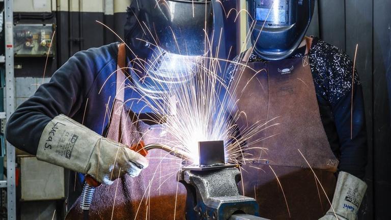 Auszubildende mit Schutzmasken beim Schweißen. Auszubildende mit Schutzmasken beim Schweißen.