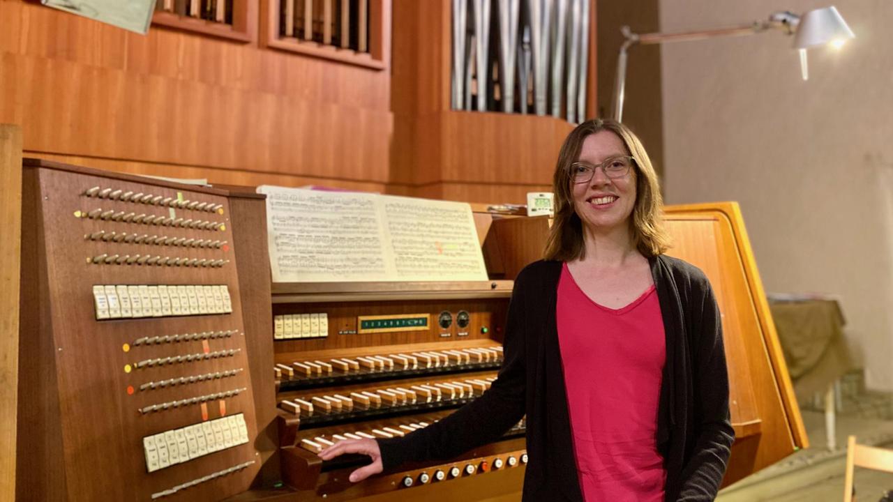 Eine Frau sitzt an drei Tastaturen einer Orgel.