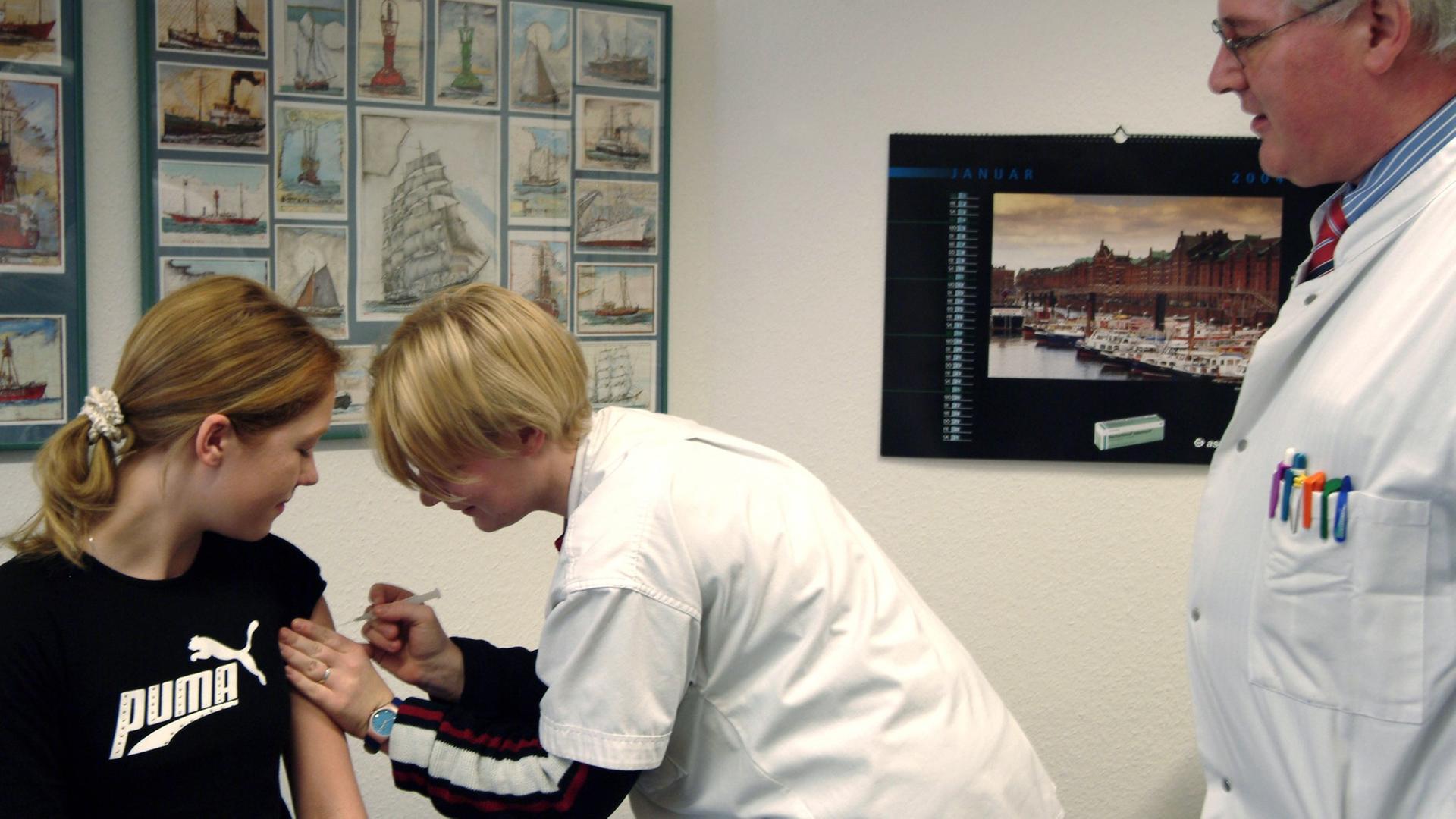 Eine Patientin wird in der Praxis eines Hausarztes (r) vor einer Reise ins Ausland von der Sprechstundenhilfe geimpft.