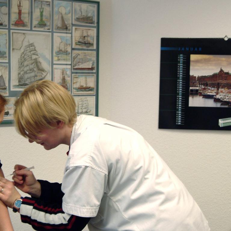 Eine Patientin wird in der Praxis eines Hausarztes (r) vor einer Reise ins Ausland von der Sprechstundenhilfe geimpft.
