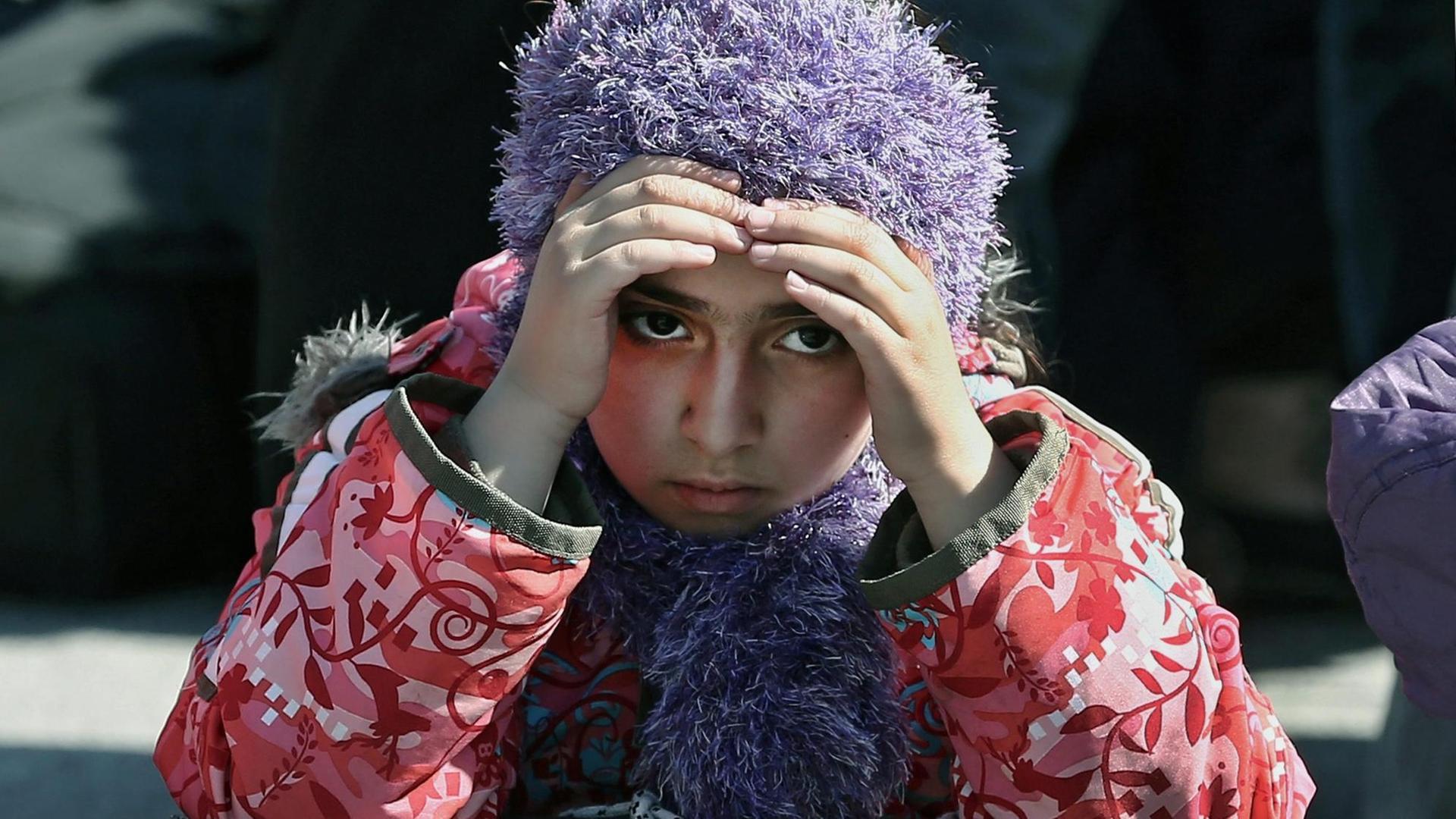 Ein junges Flüchtlingsmädchen hält sich im Hafen von Piräus die Stirn mit ihren Händen.