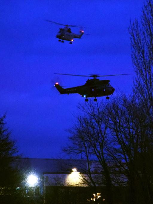 Helikopter kreisen am Abendhimmel über einem Industriegebäude in Dammartin-en-Goële nahe Paris.