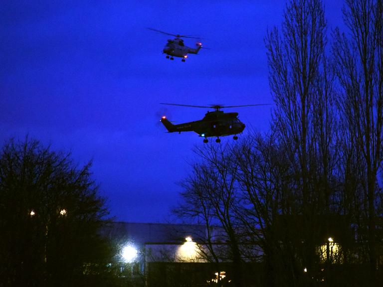 Helikopter kreisen am Abendhimmel über einem Industriegebäude in Dammartin-en-Goële nahe Paris.