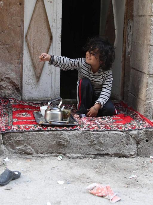 Ein syrischer Junge sitzt vor seinem Haus in Tishreen am ersten Tag des Waffenstillstands in Syrien.