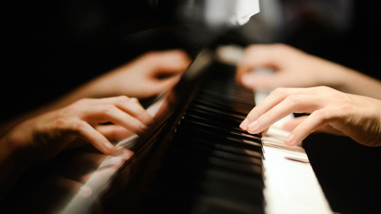 Ein Pianist spielt auf den Tasten eines Klaviers.