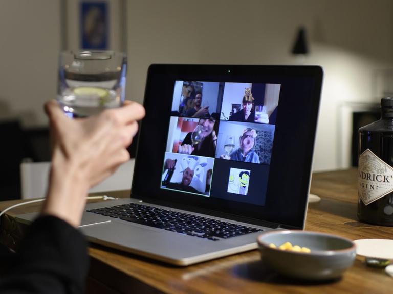Eine Frau hält bei einem Zoom-Meeting einen Cocktail in der Hand.