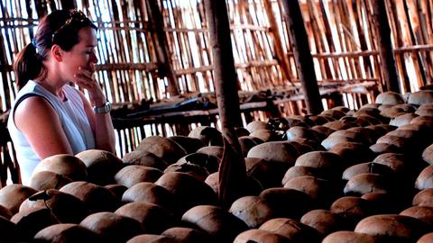 Eine Frau steht vor einer Schädelreihe: Gedenkstätte für den Völkermord in Ruanda