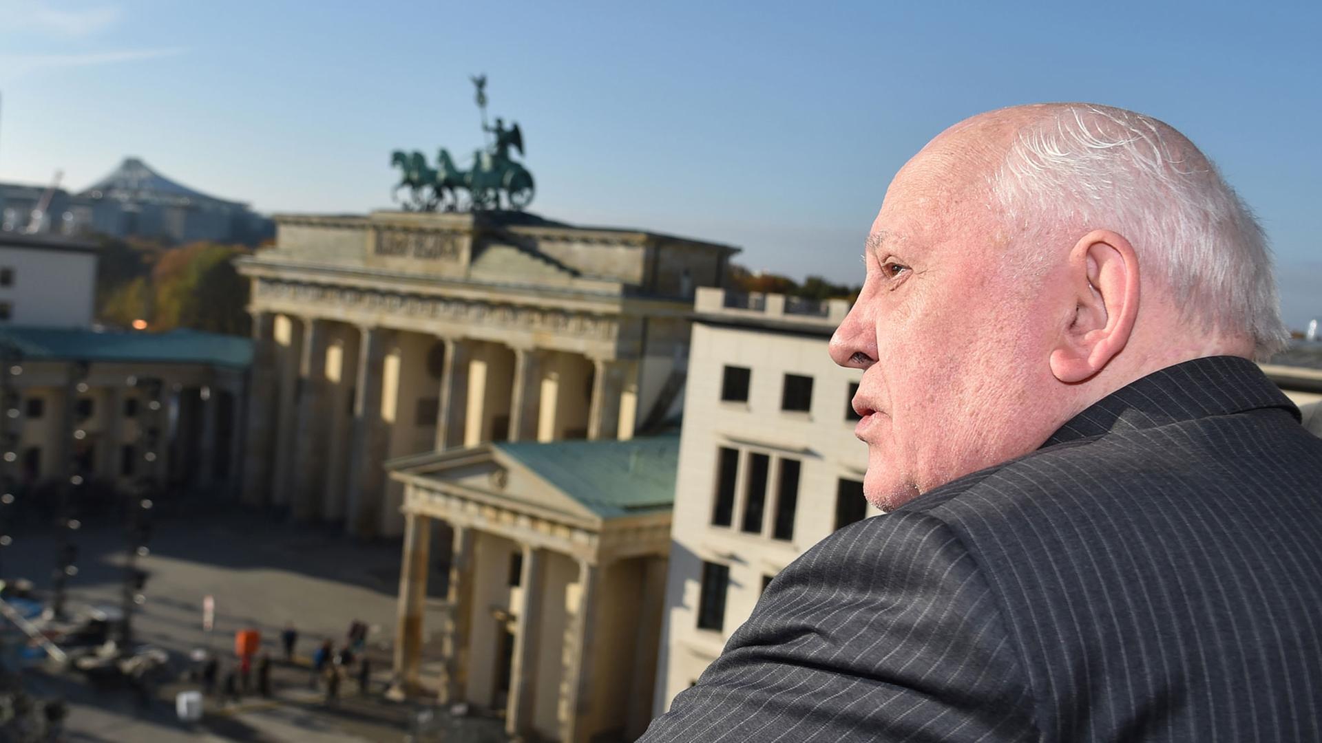 Der frühere sowjetische Staatspräsident Michail Gorbatschow steht am Pariser Platz in Berlin mit Blick auf das Brandenburger Tor.