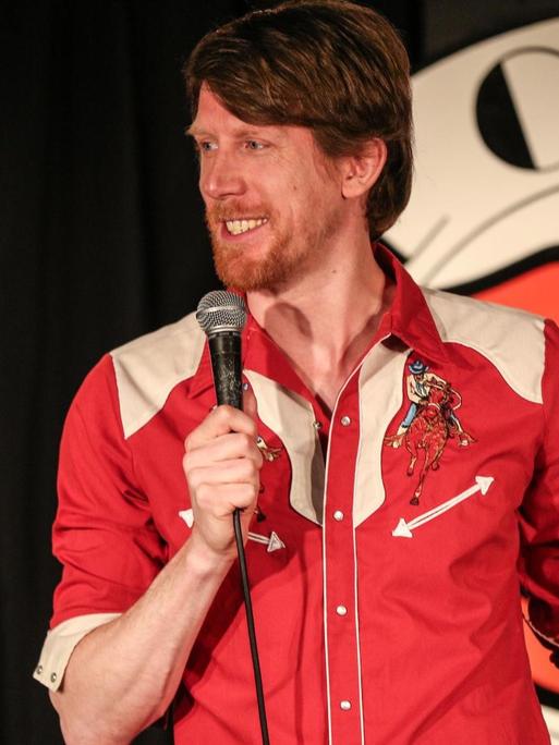 Der Komiker Christian Schulte Loh auf einer Bühne vor dem Logo des renommierten Londoner "Comedy Store"