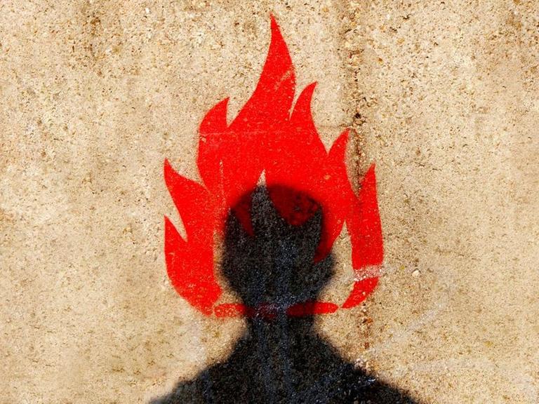 Auf einer verputzten Häuserwand ist ein stilisierter schwarzer Männerkopf mit einer roten Flamme zu sehen.