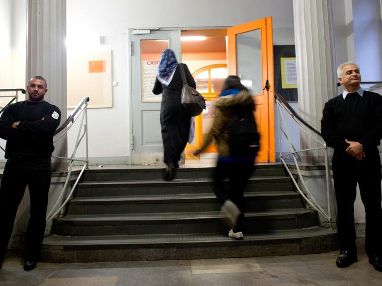 Zwei Mitarbeiter einer Sicherheitsfirma bewachen an der Berliner Albert-Schweitzer-Schule den Eingang