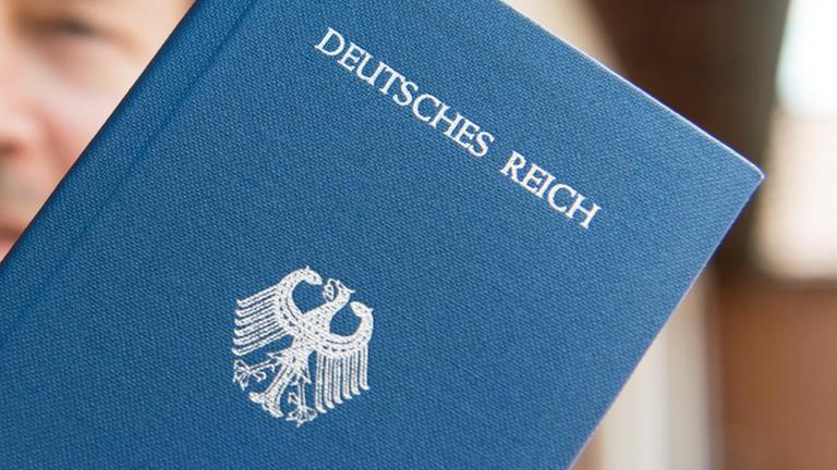 Ein "Reichsbürger" posiert mit seinem blauen "Deutsches Reich Reisepass".