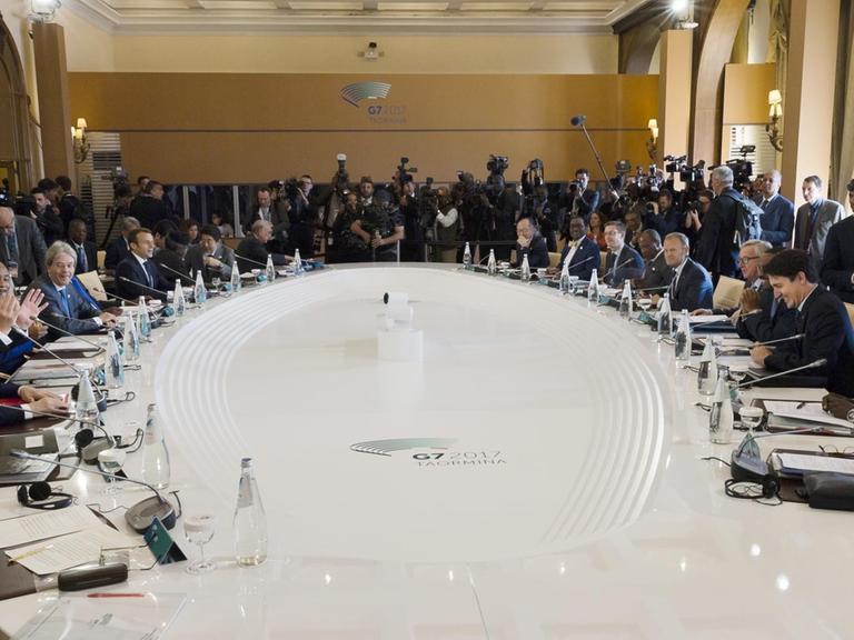 Das Foto zeigt die Staats- und Regierungschefs der sieben größten Industrienationen, G7. Sie beraten sitzend an einem Tisch in großer Runde am zweiten Gipfeltag in Taormina auf Silizien.