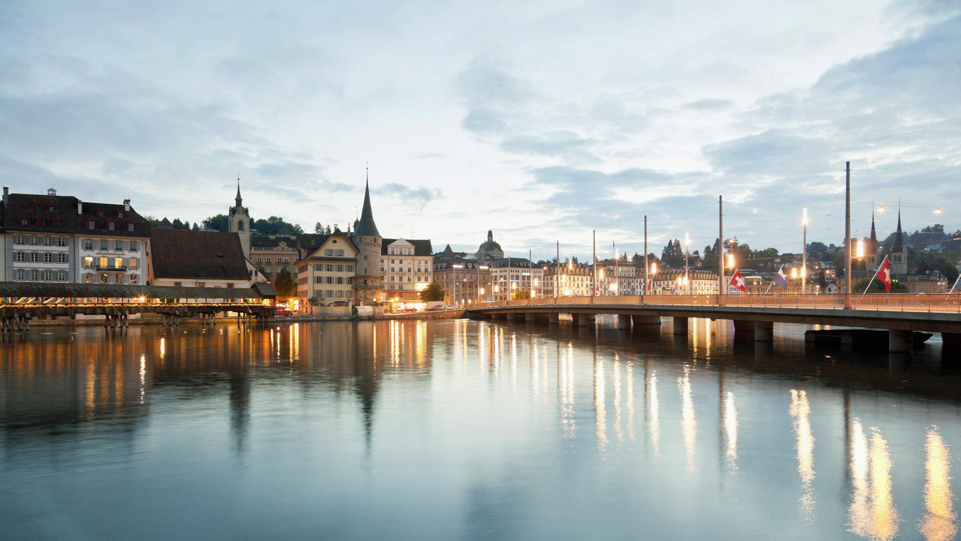 Die Stadt Luzern in der Schweiz im Dämmerlicht, auch die Straßenlaternen leuchten hell.