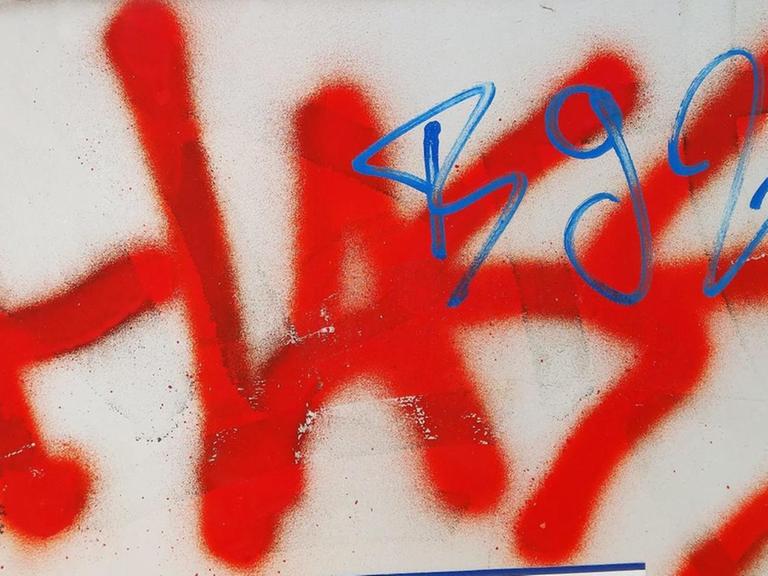 Das Wort "Hass" steht gesprüht in roter Farbe auf einem Stromkasten.
