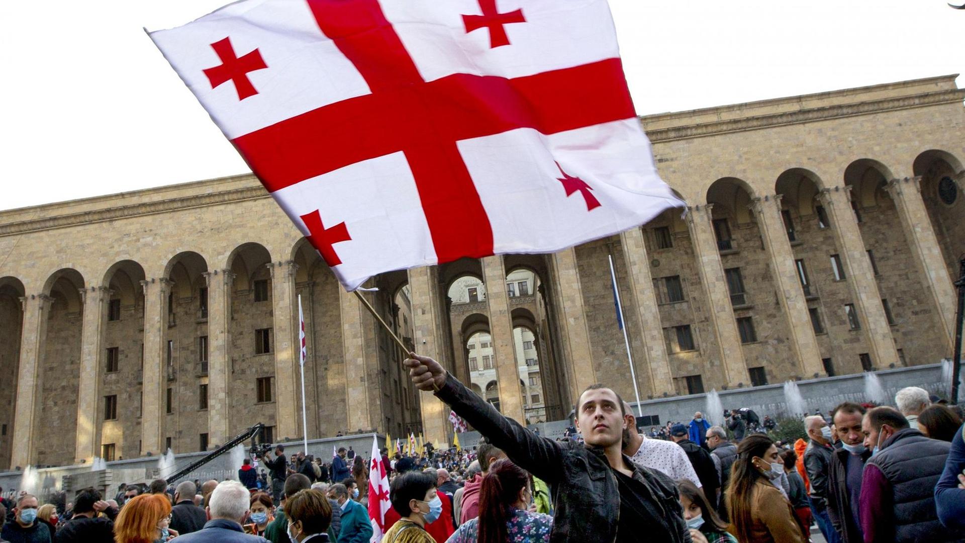 Ein Unterstützer der Vereinigten Nationalen Bewegung des georgischen Ex-Präsidenten Saakaschwili schwenkt eine Fahne vor dem Parlamentsgebäude während eines Protestes gegen die Wahlergebnisse.