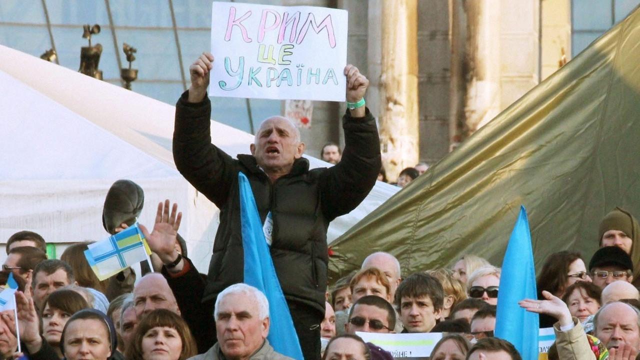 Ein Aktivist in der ukrainischen Hauptstadt Kiew hält ein Transparent mit der Aufschrift "Die Krim gehört zur Ukraine" hoch.