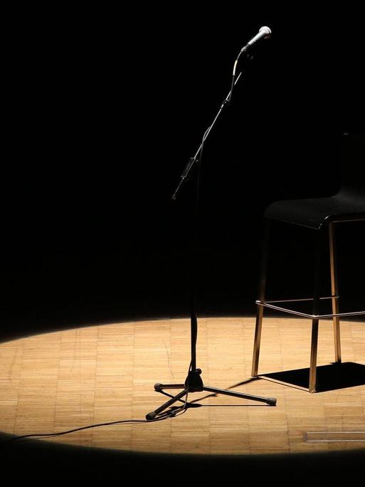Mikrofonständer und Stuhl auf einer leeren Bühne.