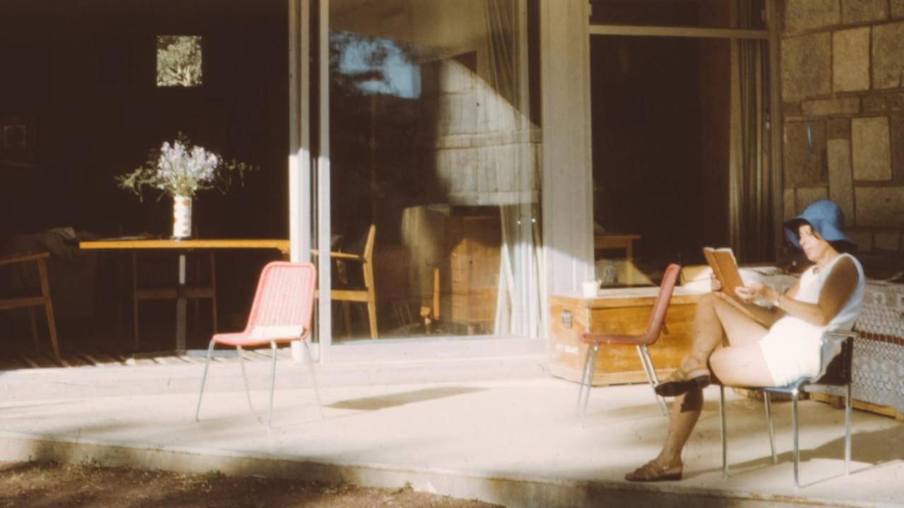 Eine Frau sitzt auf einem Stuhl und liest ein Buch. Das Bild ist vermutlich aus den 70er Jahren und der Zeit entsprechend atmosphärisch.