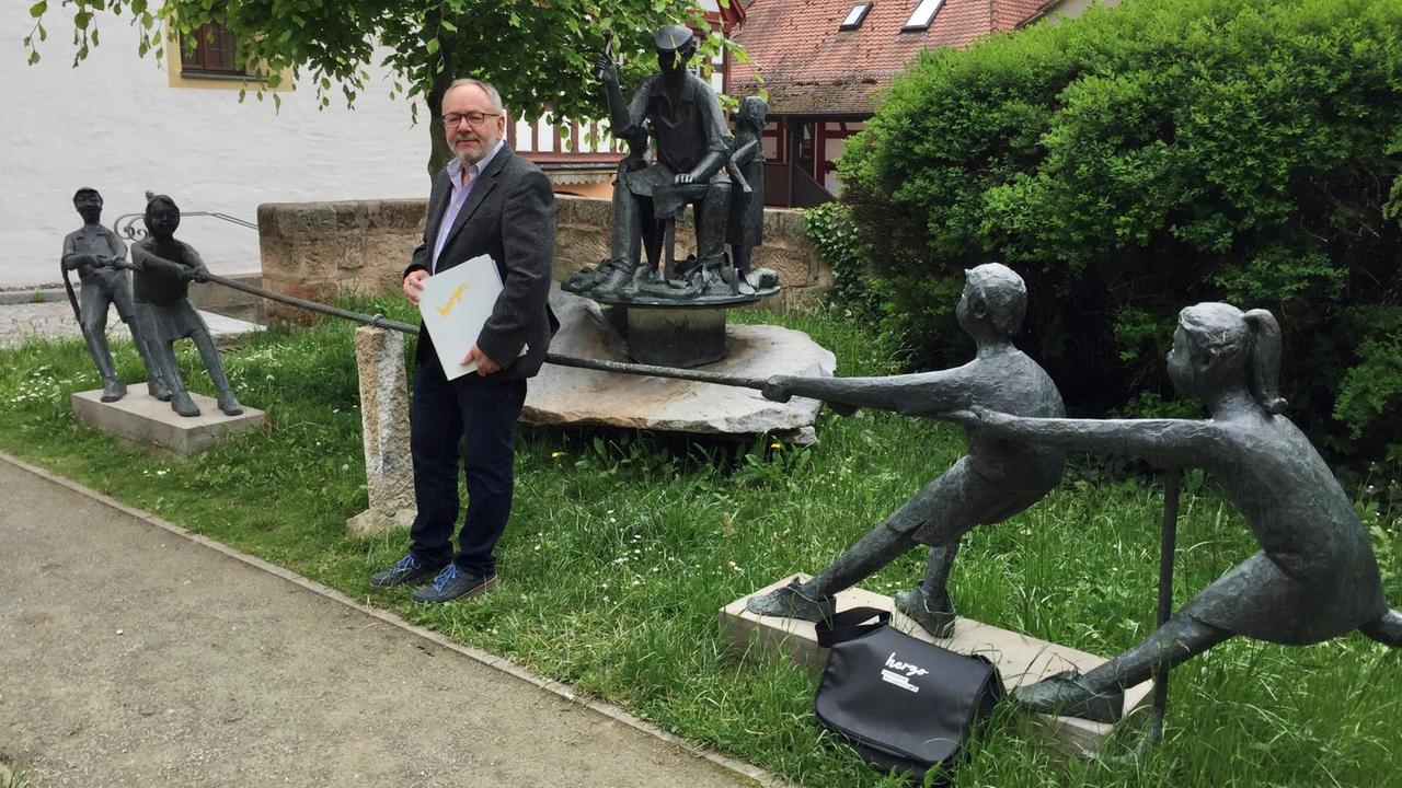 Stadtführer Dieter Hagen vor dem Schusterbrunnen in Herzogenaurach. Der Brunnsn ist ein Symbol für das Schuster-Handwerk und den Wettstreit von Adidas und Puma.