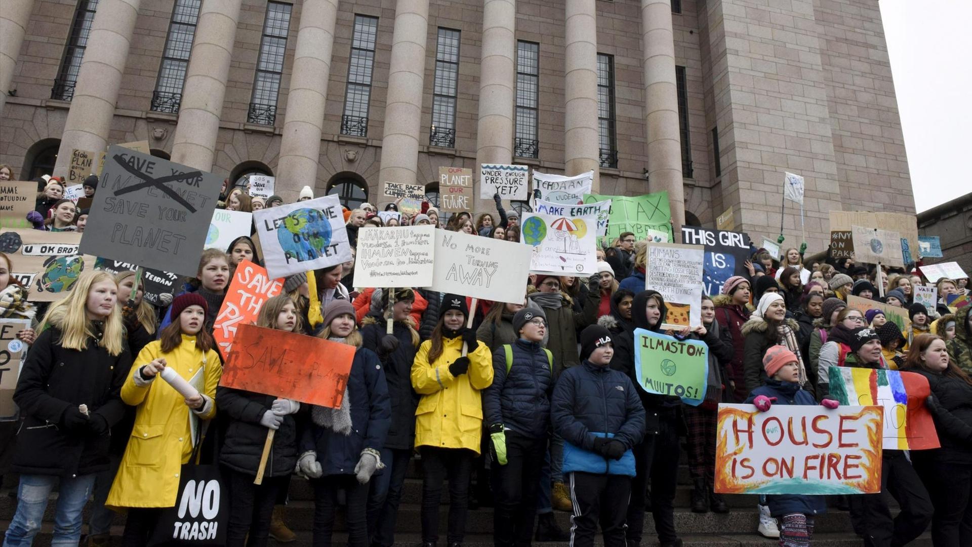 Junge Menschen stehen auf den Stufen des finnischen Parlaments und demonstrieren für mehr Klimaschutz.