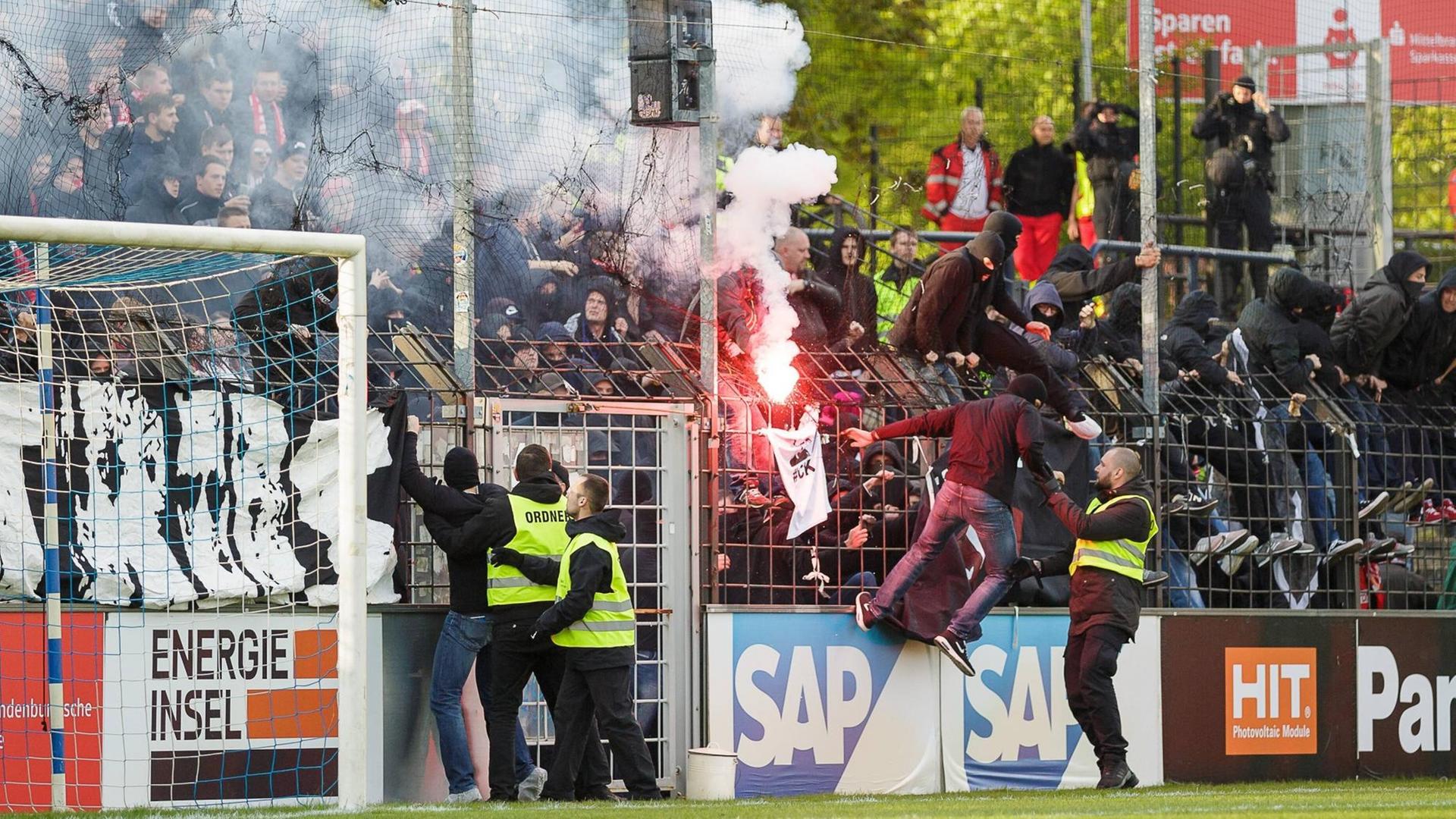 Cottbusser Fans zünden Pyrotechnik und stürmen den Platz.