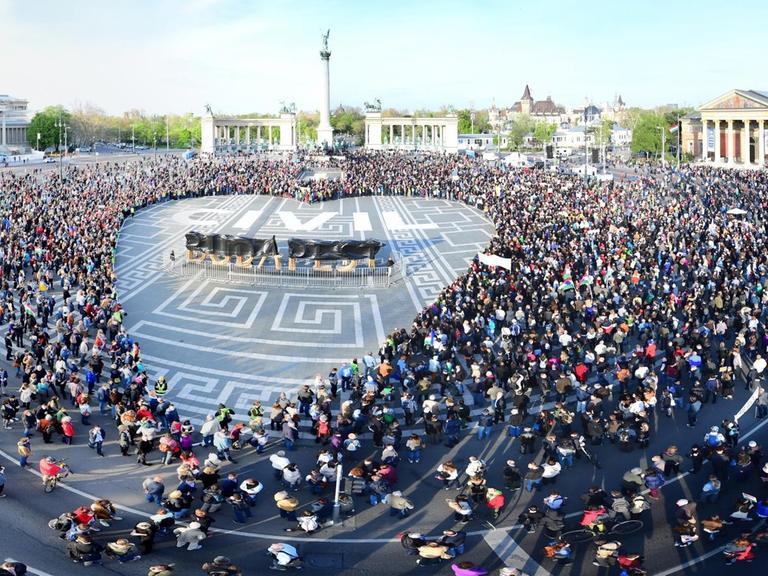 Tausende Ungarn demonstrieren auf dem Heldenplatz in Budapest. Sie haben ein Herz gebildet, in dessen Mitte "Zivil" steht.