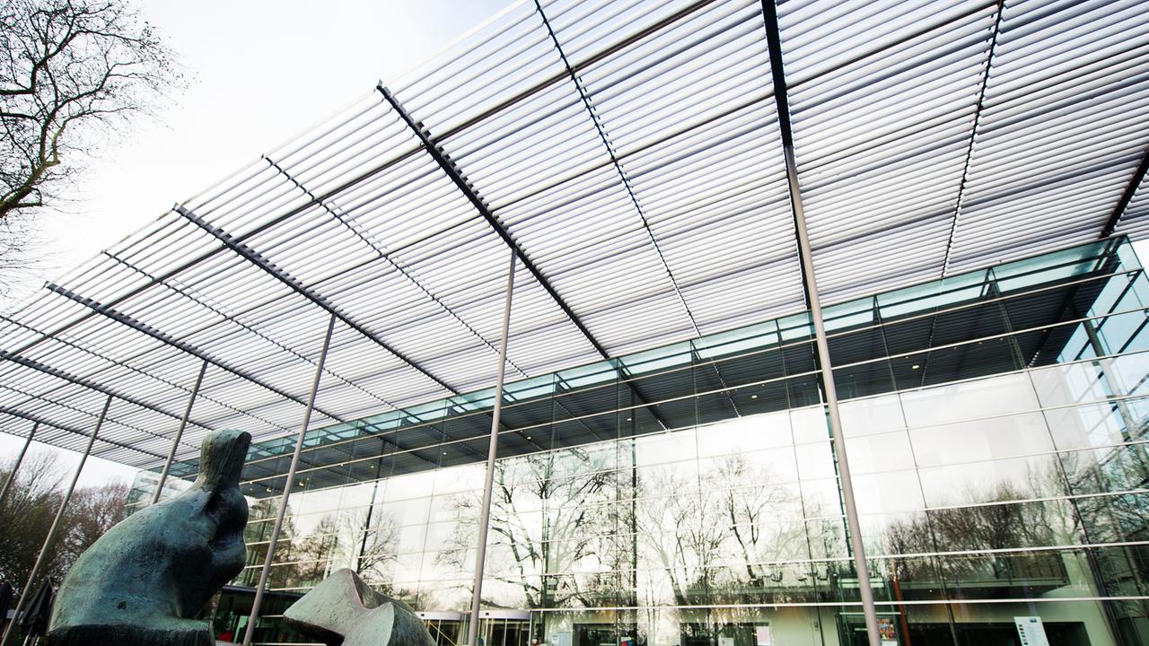 Die Halle der Ruhrfestspiele in Recklinghausen, Blick vom Boden auf ein Glasgebäude, im Vordergrund eine Skulptur