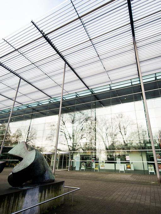 Halle der Ruhrfestspiele in Recklinghausen, Blick vom Boden auf ein Glasgebäude, im Vordergrund eine Skulptur