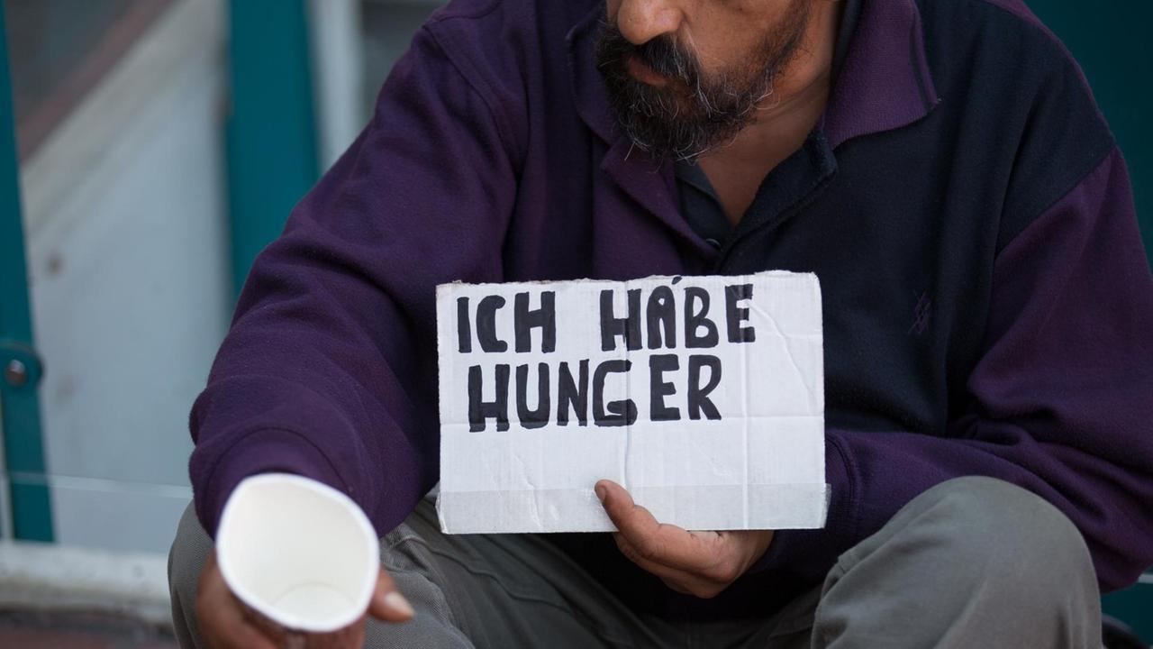 Ein Bettler hält am 14.09.2016 in Münster (Nordrhein-Westfalen) einen Becher und ein Schild mit der Aufchrift "Ich habe Hunger".