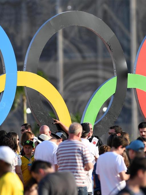 Viele Besucher stehen vor den Olympischen Ringen im Olympiapark Barra in Rio de Janeiro.