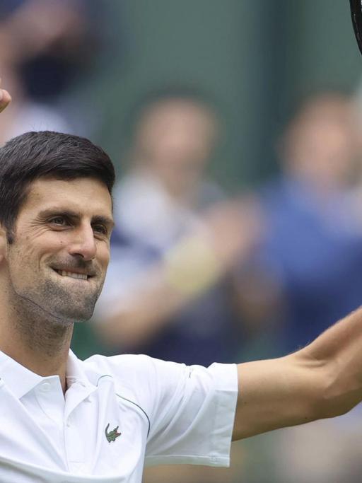 Novak Djokovic hält seinen Tennis-Schläger hoch und hebt die andere Hand zur Faust geballt nach oben.