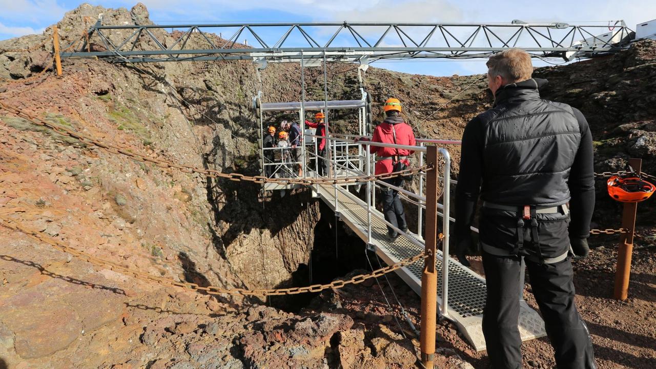 Stahlkonstruktion für den Aufzug in den erloschenen Vulkan an der Spitze des Kraters. Einige Personen sind über einen Stahlsteg in die Aufzugskabine gelangt.