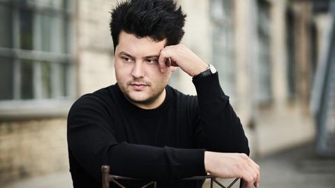 Der Schweizer Pianist Christian Erny lehnt auf einen Stuhl und blickt zur Seite.