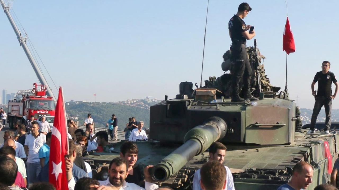 Polizisten und Erdogan-Anhänger scharen sich um einen Panzer vor der Bosporusbrücke in Istanbul.