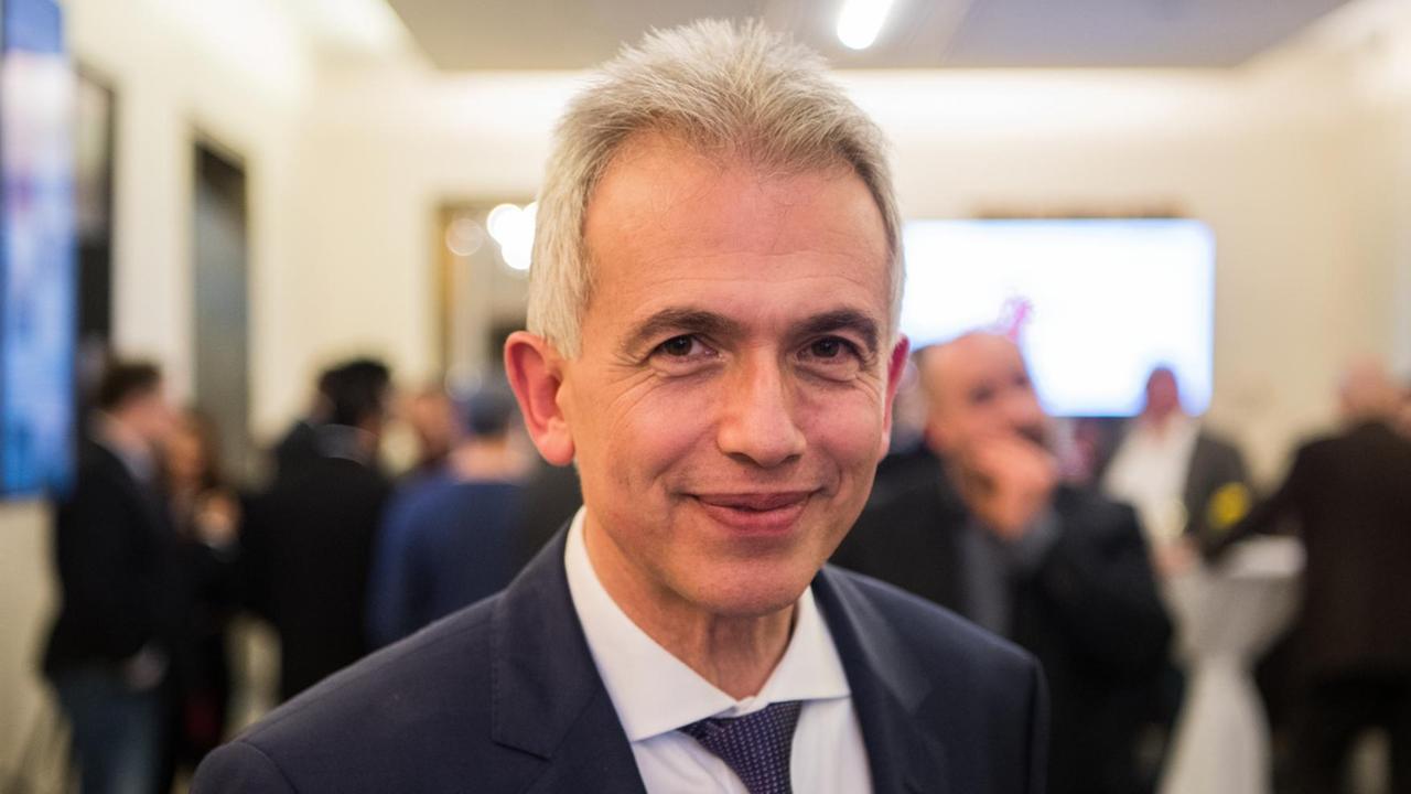 Feldmann steht in einem Raum und lächelt im schwarzen Jackett in die Kamera. Im Hintergrund unscharf weitere Menschen. Feldmann steht in einem Raum und lächelt im schwarzen Jackett in die Kamera. Im Hintergrund unscharf weitere Menschen.