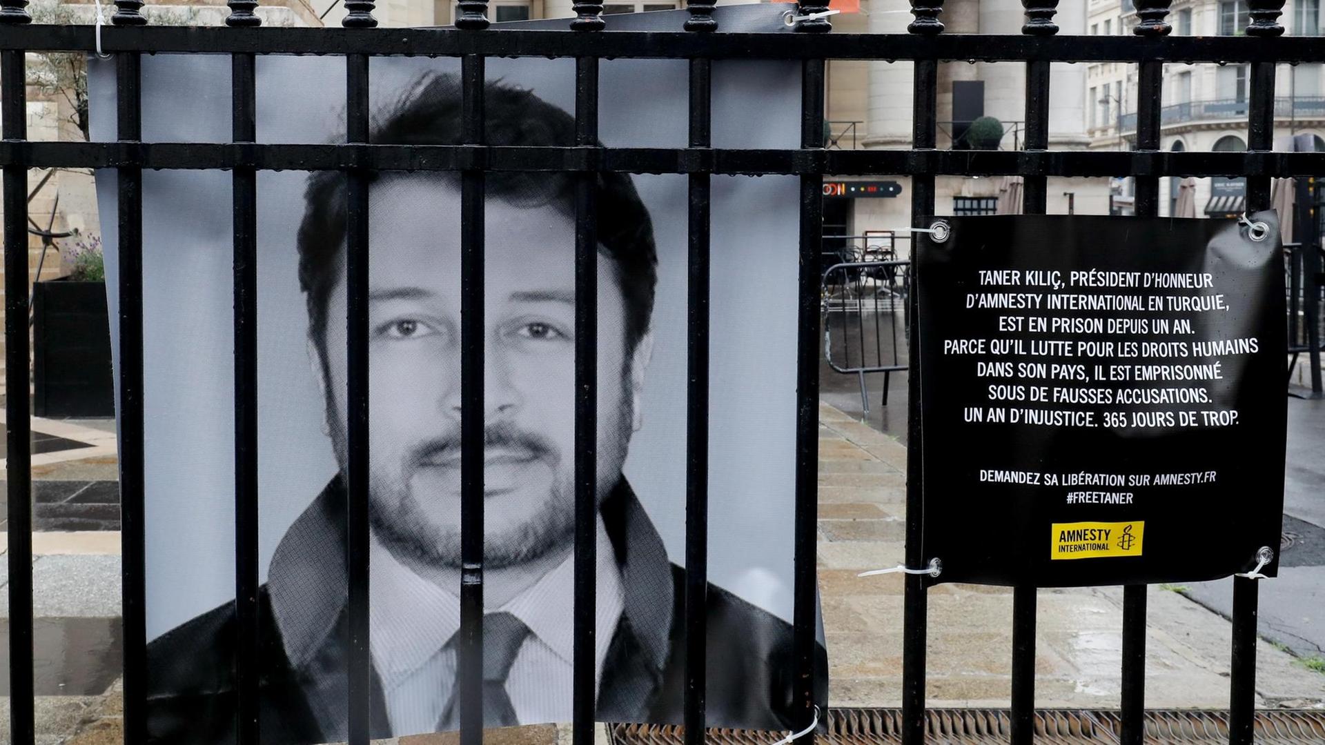 Das Foto zeigt ein Bild von dem Menschen-Rechtler Taner Kilic. Das Bild hängt hinter einem Zaun.