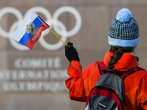 Eine Frau hält eine russische Fahne vor dem IOC-Gebäude in Lausanne.