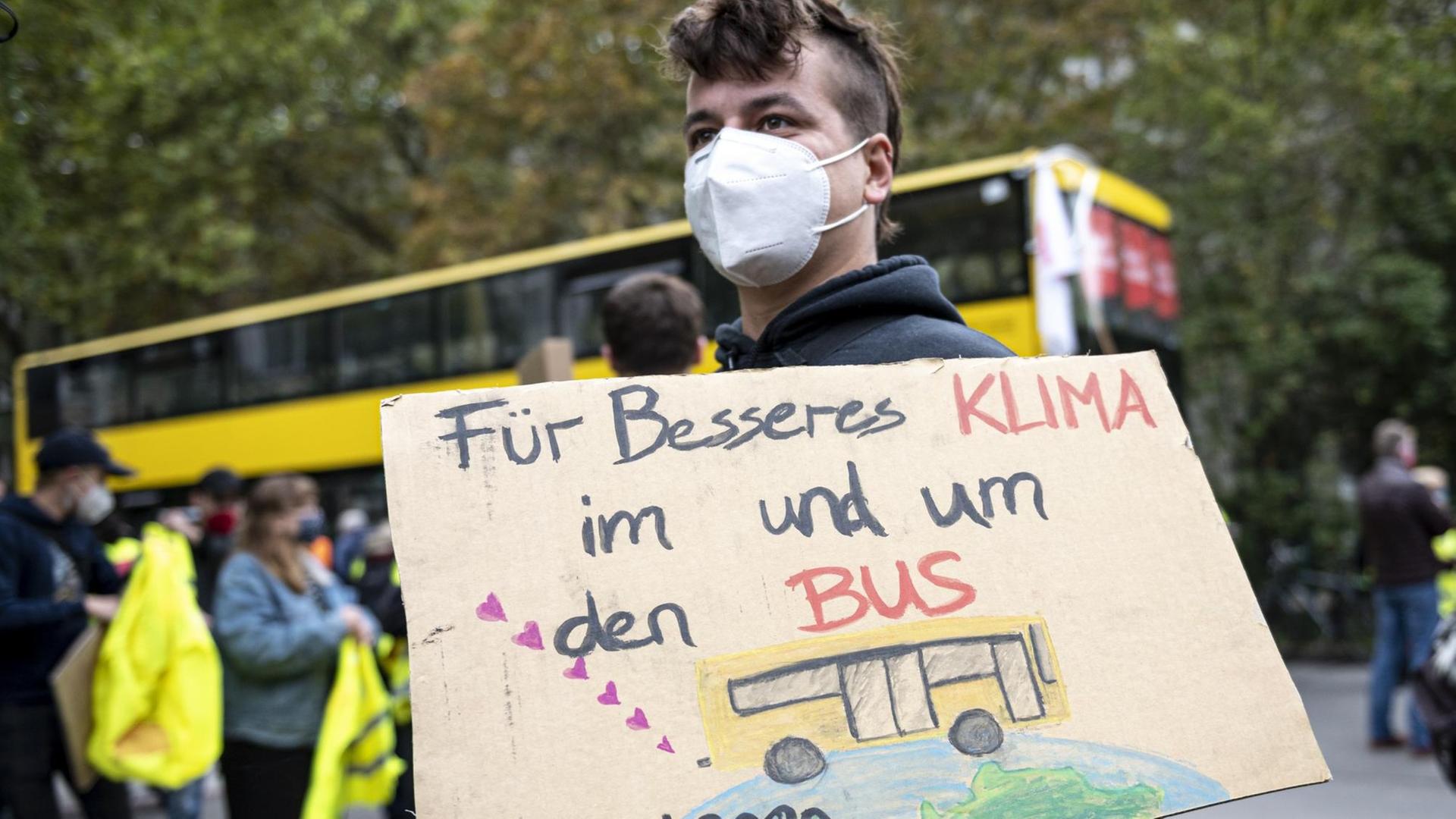 Ein Aktivist von Friday for Future steht vor dem BVG Betriebshof Cicerostraße mit einem Plakat mit der Aufschrift "Für besseres Klima im und um den Bus". Mit der Aktion will die Gewerkschaft Verdi den Druck auf die Arbeitgeber bei den anstehenden Tarifverhandlungen erhöhen.